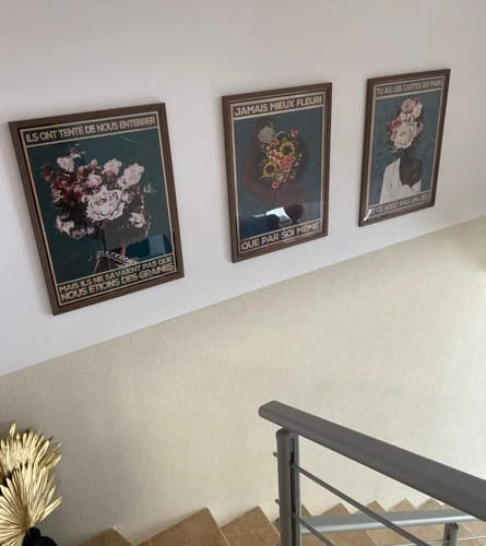 Trois toiles de Chantal installées ensemble au-dessus d’un escalier.